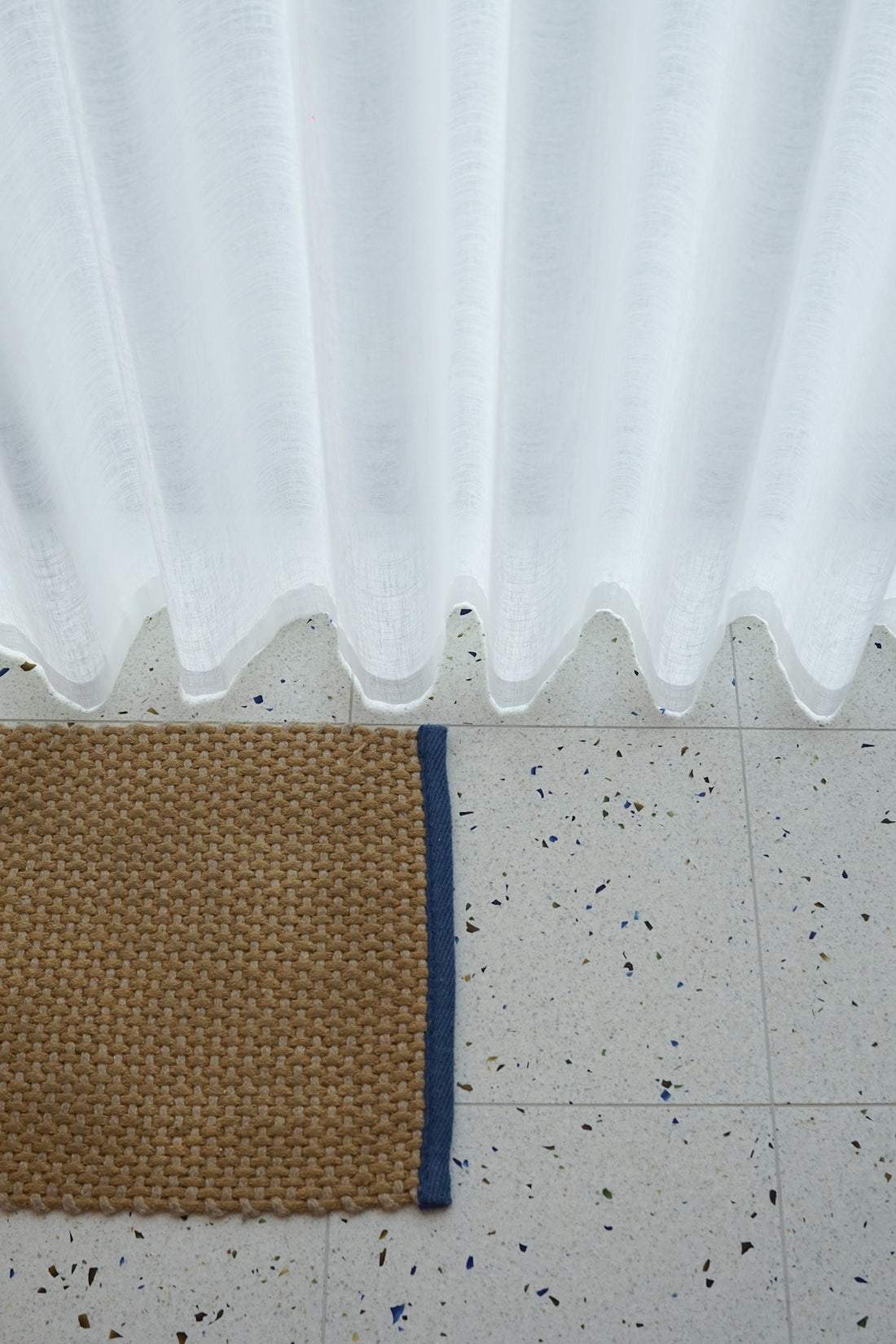 a brown and blue rug sitting on top of a tile floor