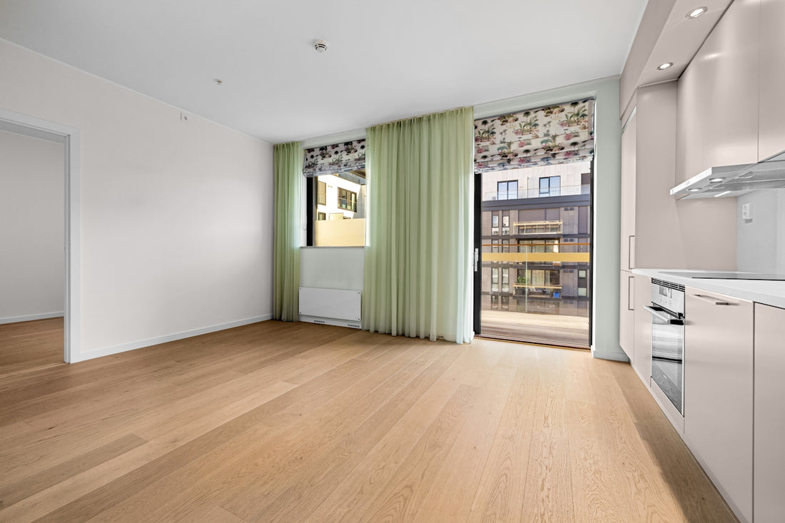 An empty room with a wooden floor and green curtains