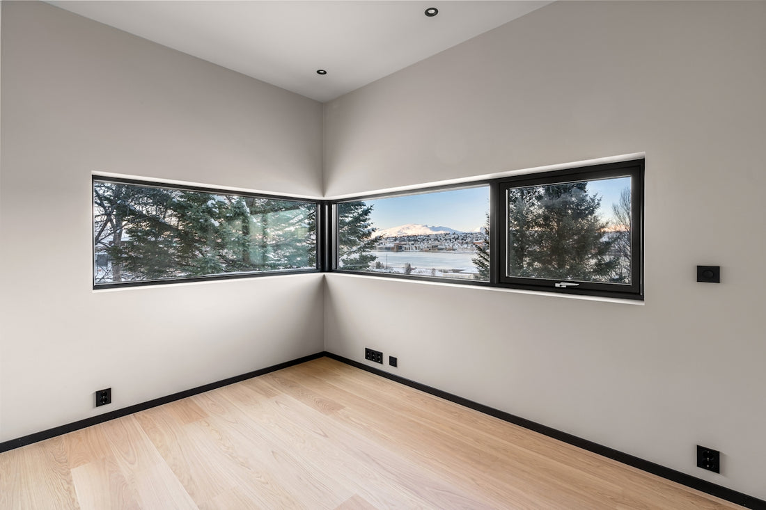 An empty room with three windows and a hard wood floor